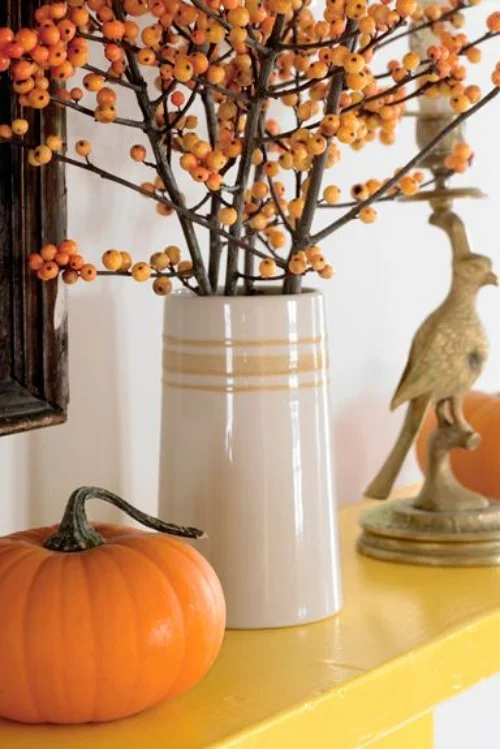 tolle Deko Ideen zu Halloween den Kaminsims dekorieren Kürbis Hagebutten Vogelfigur orange gelb beige