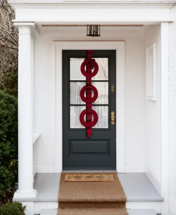 Weihnachtskranz drei rote Kreise auf kariertem Band Akzent draußen an der Haustür