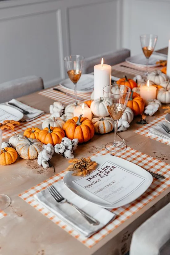 Esszimmer herbstlich dekorieren Esstisch schmücken orangefarbene und weiße Kürbisse weiße Kerzen passendes Tischgedeck