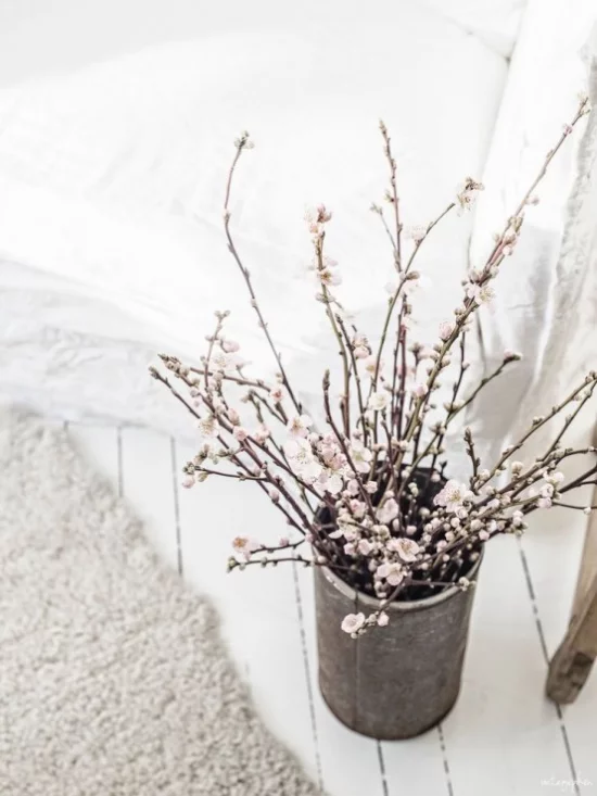 Frühlingsdeko mit Kirschblüten weiße Blüten im alten Gefäß im Wohnzimmer