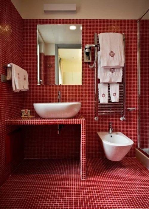 Badezimmer in Rot Wände Boden Waschtisch mit kleinen roten Fliesen bedeckt weißer Mörtel WC Waschbecken Handtücher weiß Wandspiegel