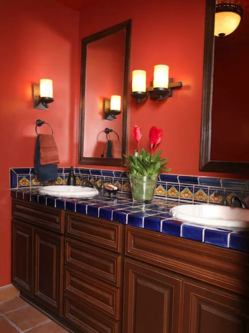 Badezimmer in Rot klassischer Look Waschtisch mit dunkelblauen Fliesen im Retro Stil zwei runde Waschbecken Wandspiegel Wandlampen