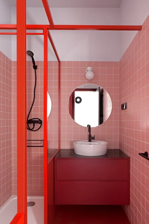 Badezimmer in Rot roter Waschtischschrank rosa Fliesen runder Spiegel Duschecke