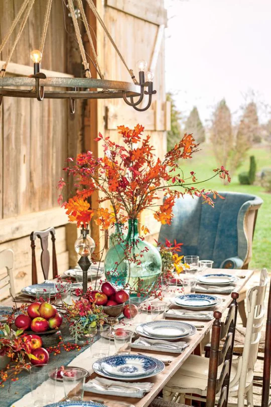 Deko Ideen mit Herbstblättern festlich gedeckter Tisch draußen Vase mit bunten Blättern Blickfang rote Äpfel Beeren