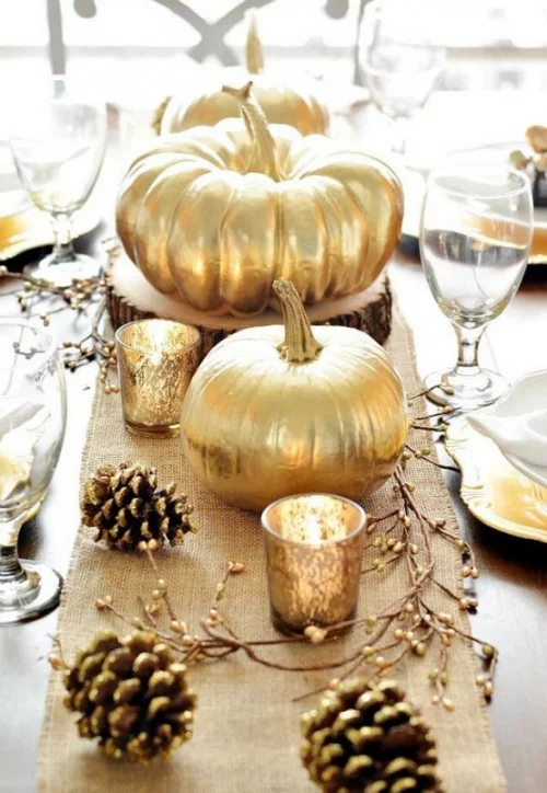 Herbstdeko mit Tannenzapfenzapfen Zierkürbisse im Goldglanz festlich gedeckter Tisch