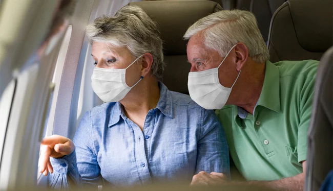 Fliegen während Corona Ansteckungsgefahr für ältere Leute höher Mann Frau über 65 im Flugzeug