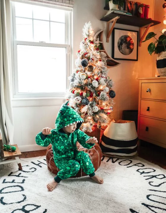Kinderzimmer weihnachtlich dekorieren Spielparadies schön dekorierter Christbaum kleiner Junge vorne auf dem Teppich
