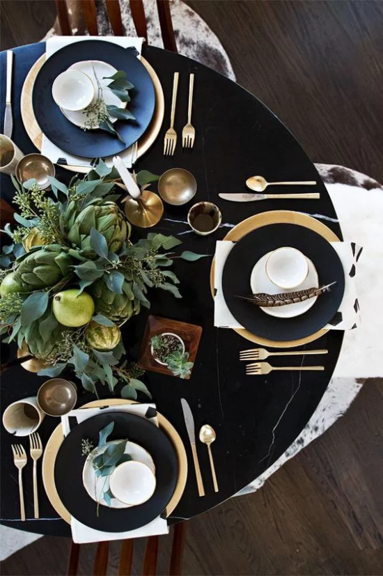 Silvester feiern zu Hause schön arrangierte Festtafel Service in Gold und Schwarz feines Besteck in der Tischmitte Vase mit grünen Zweigen