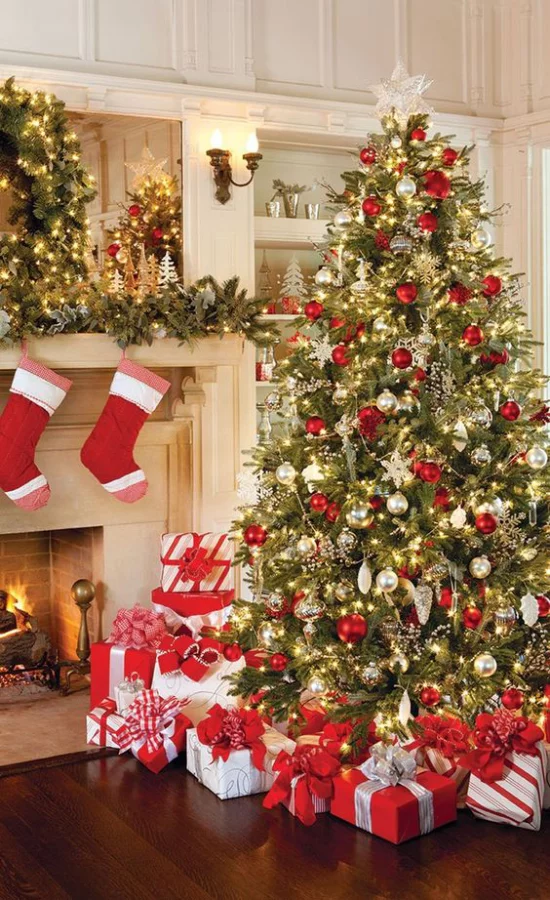 Weihnachtsdeko in Rot und Gold Weihnachtsbaum geschmückt neben dem Kamin Nikolausstiefel am Kaminsims zahlreiche Geschenke Lichter