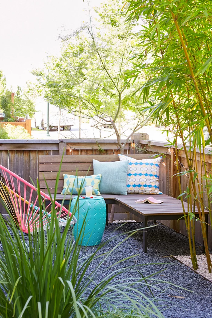 Kleinen Hinterhof gestalten Ecksitzbank am Zaun Deko Kissen Sessel aus Metall hohe grüne Pflanzen