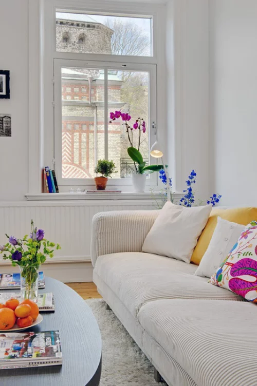 frühlingshafte Dekoideen für das Wohnzimmer helles Sofa schönes Ambiente verschiedene Frühlingsblumen in Vasen und Töpfen Dekokissen