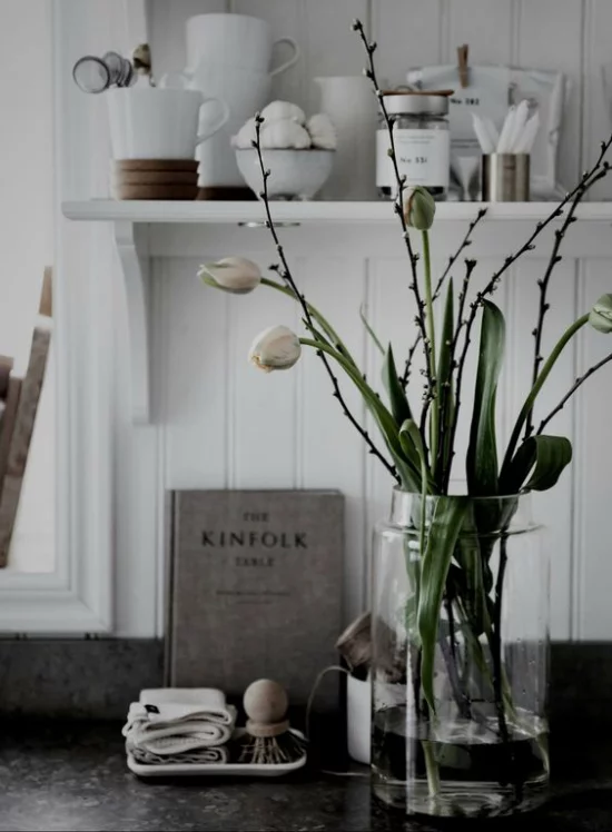skandinavische Frühlingsdeko Vase aus Glas weiße Tulpen weitere Deko Artikel dunkelgrauer Hintergrund