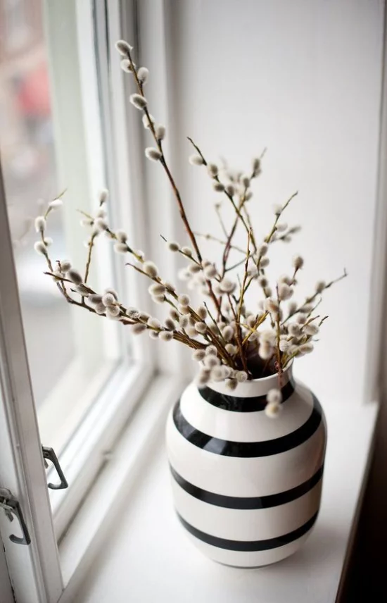 skandinavische Frühlingsdeko Vase blühende Zweige am Fenster platziert