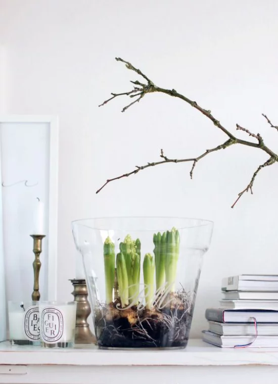 skandinavische Frühlingsdeko auf dem Kaminsims Hyazinthen im Glas Bücher Kerzen Zweige