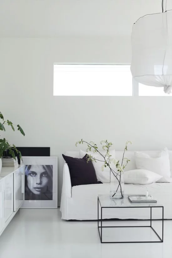 skandinavische Frühlingsdeko sehr elegantes Interieur weiße Möbel großes Bild Glastisch Glasvase Zweige