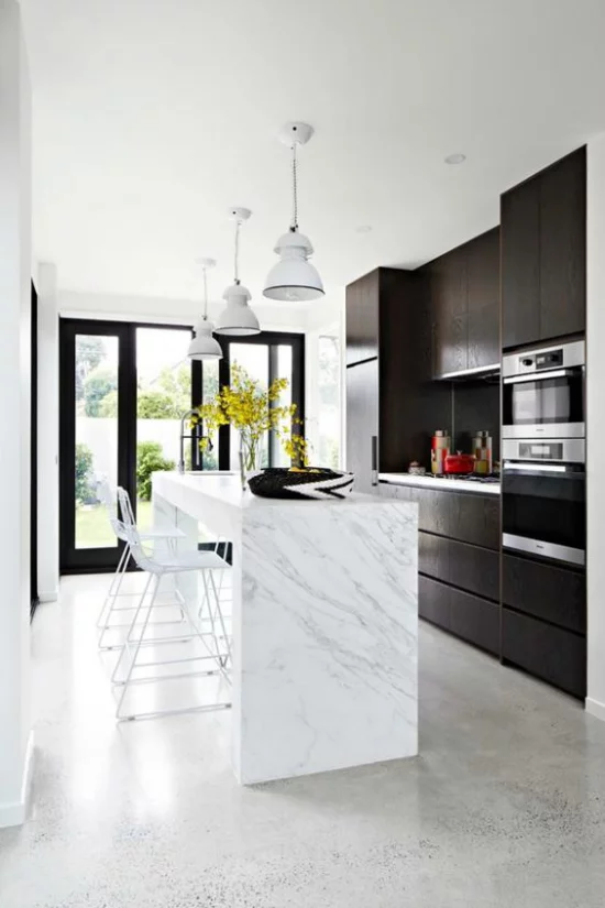 grauer Boden Beton moderne Küche weiße Kücheninsel schwarze Schränke Hängeleuchten