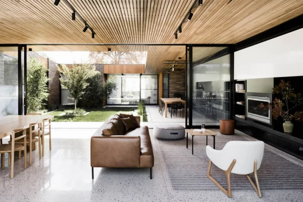 Open-Air-Wohnzimmer luxuriöses Raumkonzept großzügige Gestaltung Bodenbelag  graues Mosaik warme Holzfarben viel Grün draußen