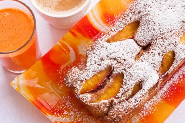 Aprikosenkuchen serviert frischer Geschmack daneben ein Glas Saft und eine Tasse Kaffee