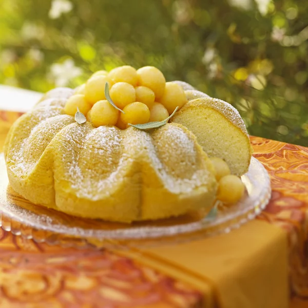 Melonen Desserts Zitronenkuchen mit Melonenbällchen und Puderzucker garnieren