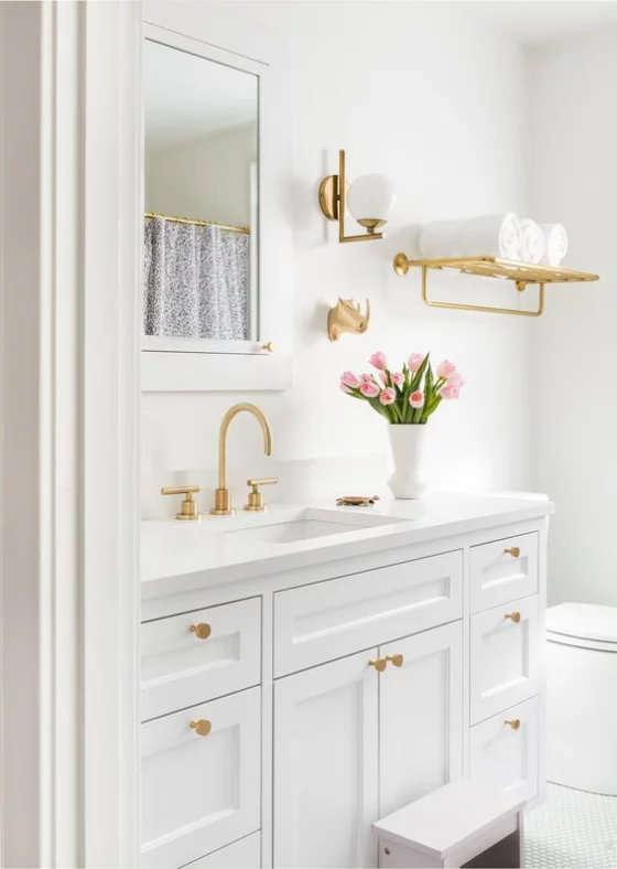 Goldene Akzente im Interieur weißes Bad goldgelbe Griffe an den Schränken Armatur Spiegel weiße Vase mit rosa Tulpen