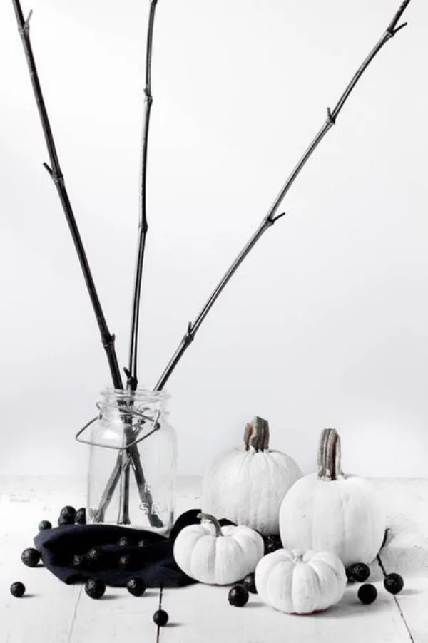 minimalistische Halloween Deko kleine weiße Kürbisse schwarze Bälle Glas kahle Zweige
