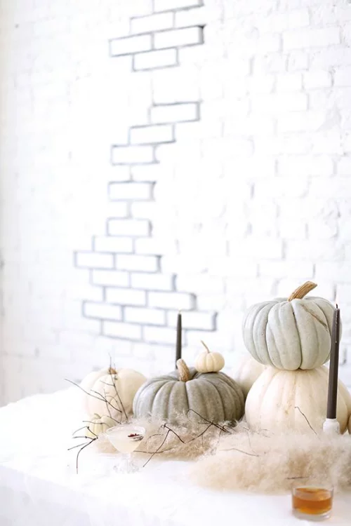 natürliche Halloween Deko Kürbisse unterschiedliche Größe und Farbe auf einem Tisch vor der weißen Ziegelwand arrangieren