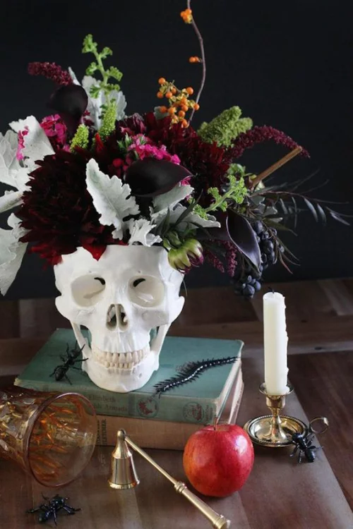 natürliche Halloween Deko weißer Totenkopf als Vase auf dem Tisch mit schönen Blumen aus dem Garten gruselig