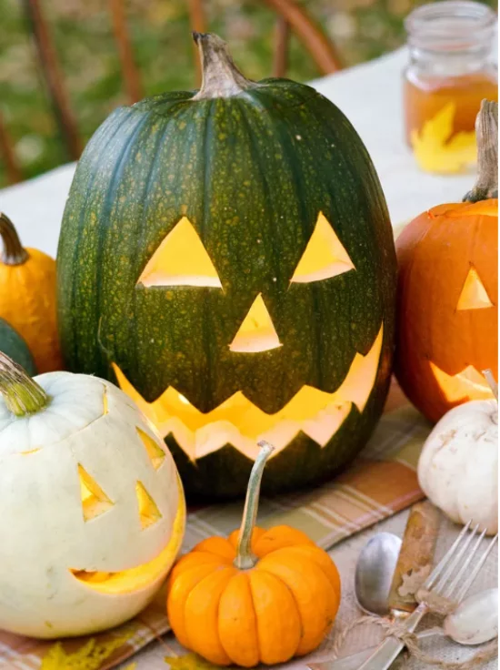 Herbstdeko mit Kuerbissen geschnitzte Kuerbisse gruselige Halloween Gesichter Laternen