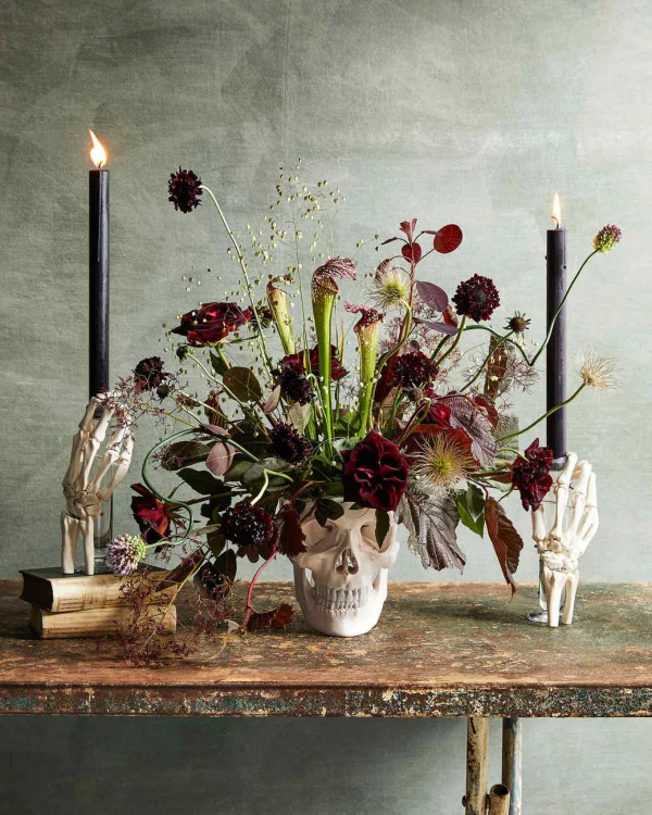 Herbstliche Tischdeko Totenkopf als Vase schoene Blumen in dunklen Farben Halloween Deko schwarze Kerzen