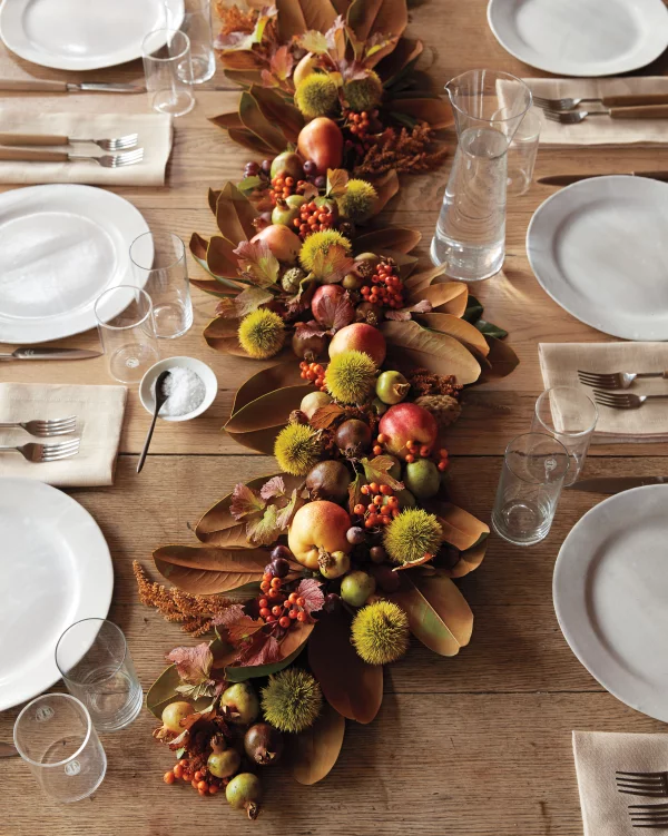 Herbstliche Tischdeko direkt aus der Natur vergilbte Bläaetter Aepfel Wildbeeren Graeser in der Tischmitte arrangiert