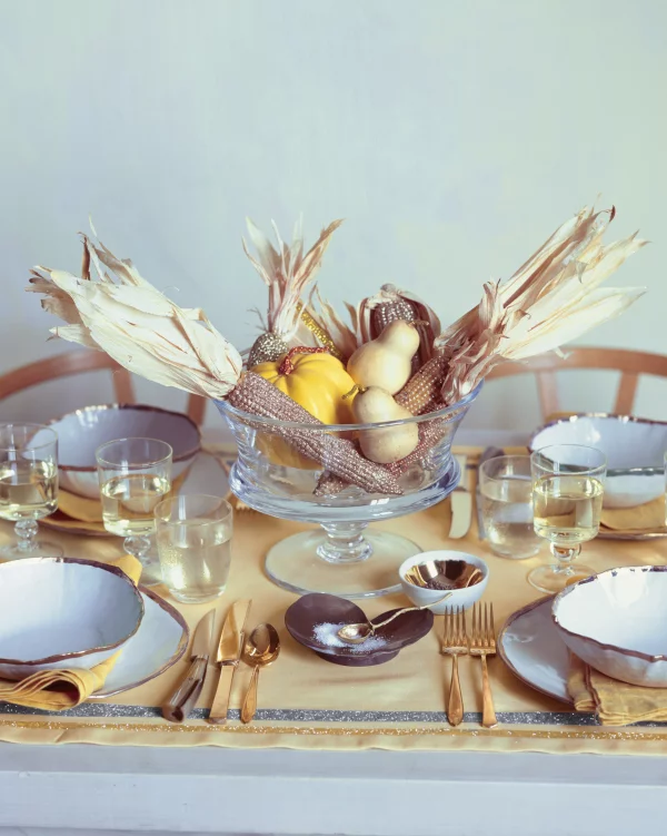 Herbstliche Tischdeko gedeckter Tisch ländlicher Stil Maiskolben Kuerbis Birnen im Glasgefaess