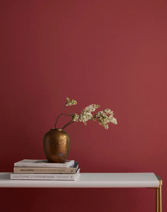 Raspberry Blush Farbe 2023 Akzentwand im Wohnzimmer auffallend schoen Vase mit weiss bluehenden Zweigen