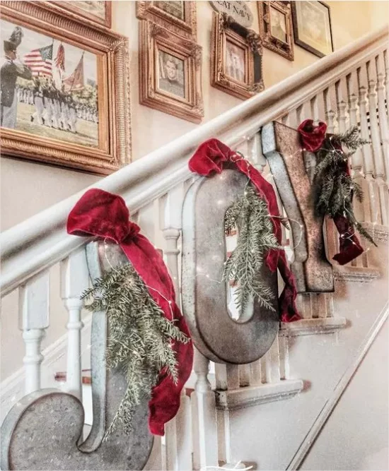 Rustikale Weihnachtsdeko drinnen Treppenhaus schmuecken Buchstaben rote Schleifen Tannenzweige