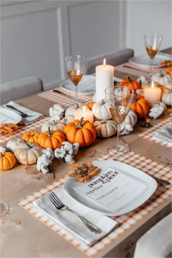 Thanksgiving in den USA orangefarbene Kürbisse weisse Kerzen schmuecken den Esstisch